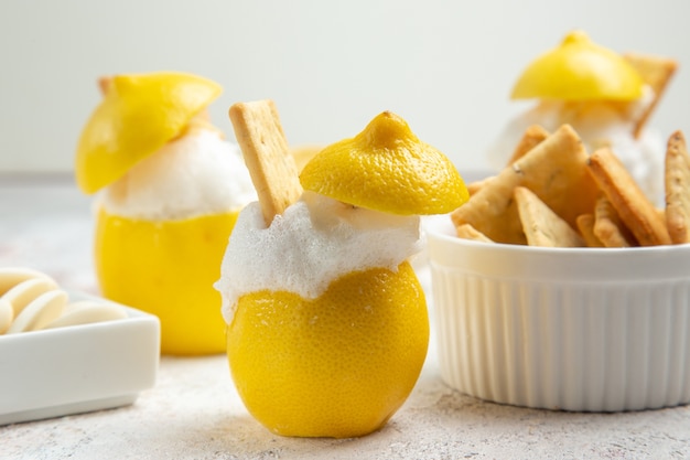 Front view lemon cocktails with ice and crackers on white table citrus cocktail juice