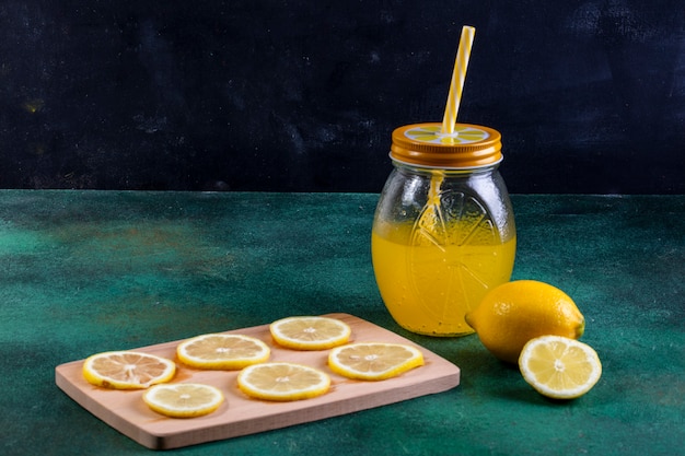 Front view lemonade in a jar of lemon and lemon slices on a blackboard