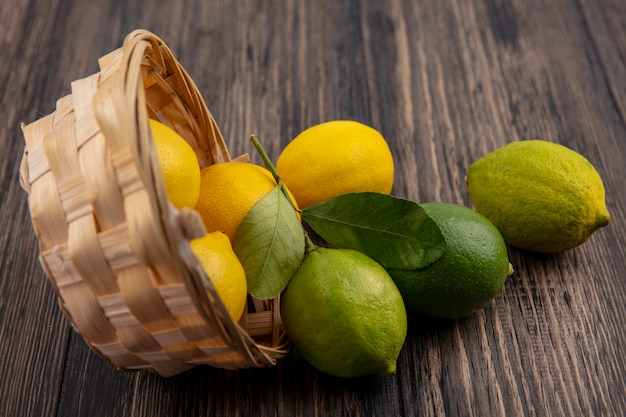 Front view lemons with limes in an inverted basket on a wooden background