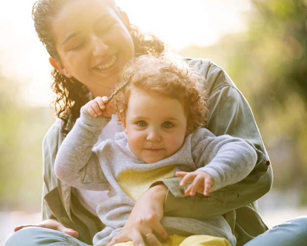 Front view of lgbt mother outdoors in the park with her kid