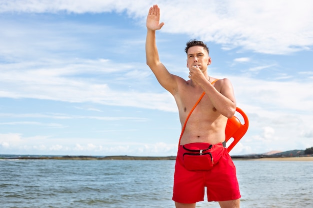 Front view lifeguard blowing whistle