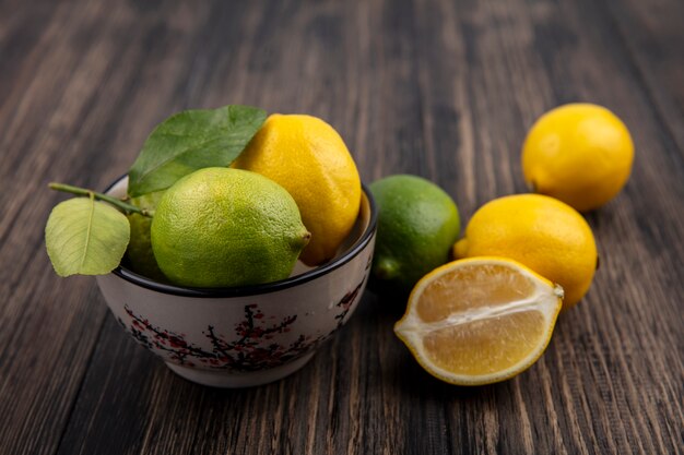 Front view limes with lemons in a bowl on wooden background