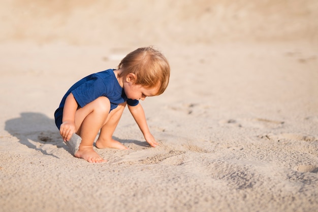 Front view little boy at beach playing