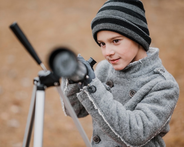 Front view little boy using a telescope