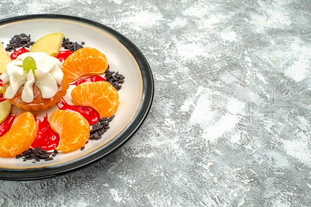 Free photo front view little cake with sliced apples and tangerines inside plate on a white background sweet fruit cake sugar biscuit cookie