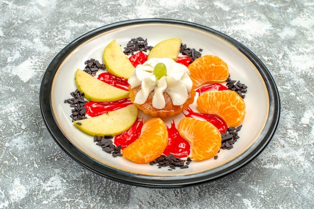 Free photo front view little cake with sliced apples and tangerines inside plate on white background sweet fruit cake sugar biscuit cookie