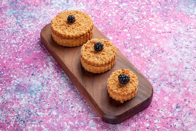 Front view of little delicious cakes round formed on the pink surface