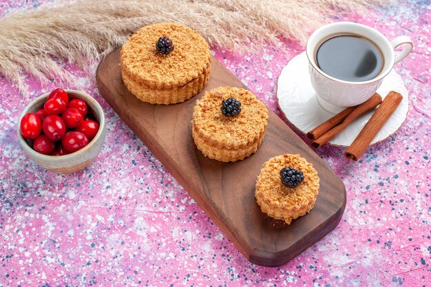 Front view of little delicious cakes round formed with cinnamon and tea on the pink surface