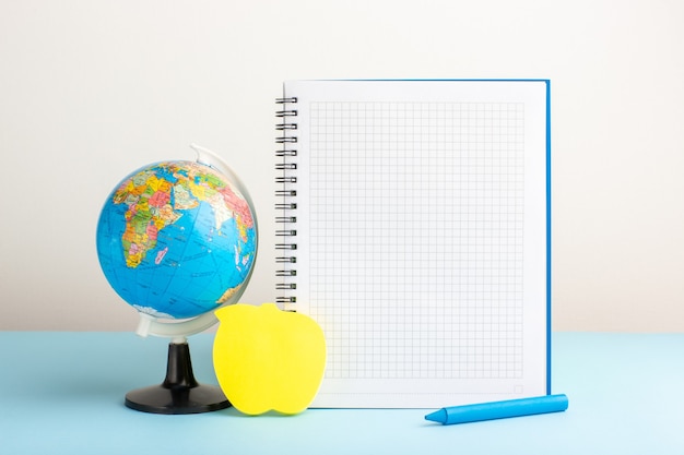 Free photo front view little earth globe with copybook on blue desk