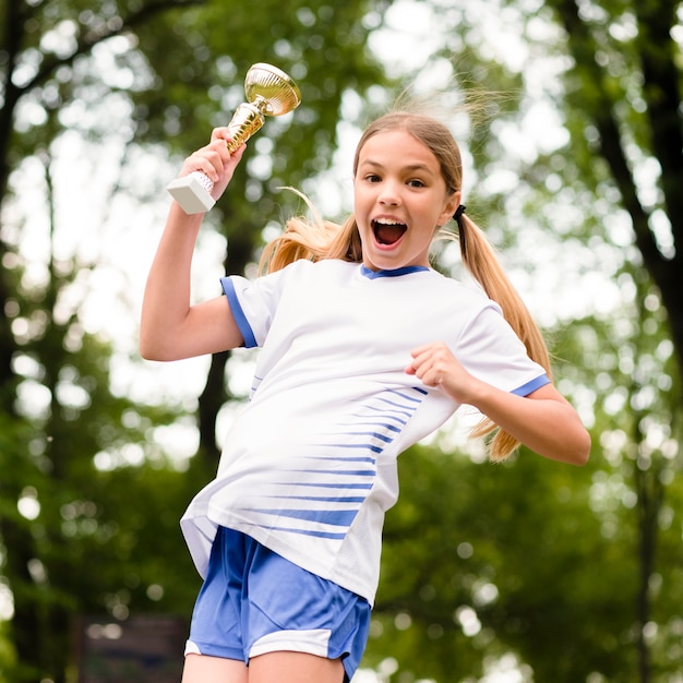 Front view little girl jumping after winning a football match