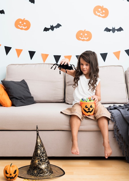 Front view little girl sitting on couch on halloween