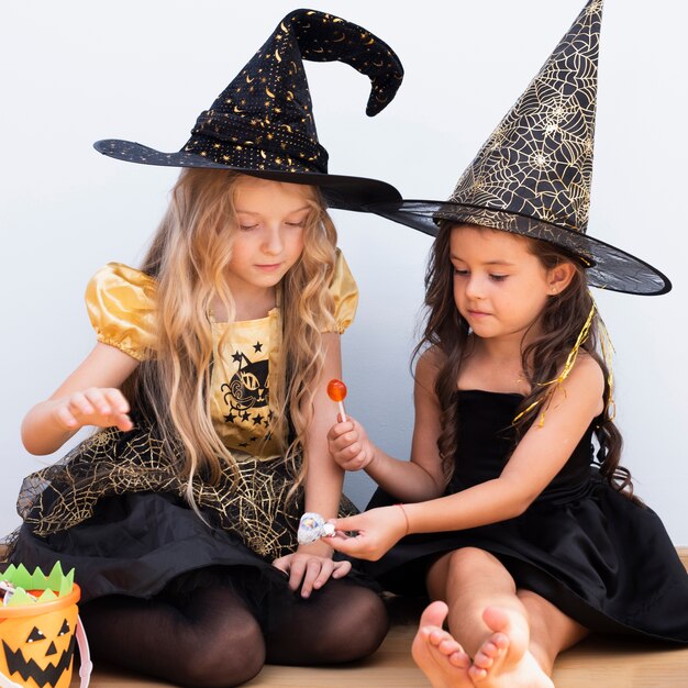 Front view little girls sitting on floor on halloween