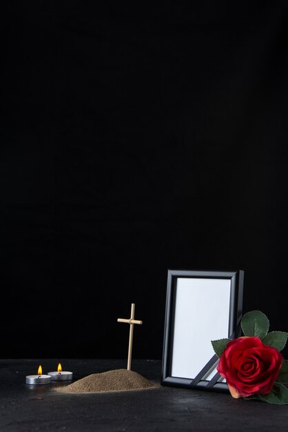 Front view of little grave with cross and picture frame on black