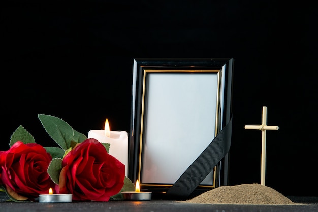 Front view of little grave with flower and candles on dark