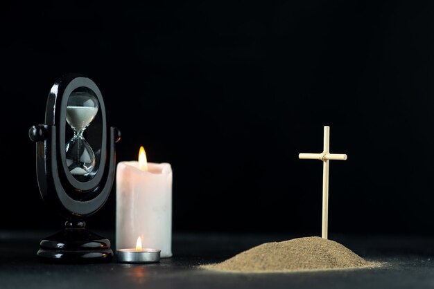 Front view of little grave with hourglass and candles dark