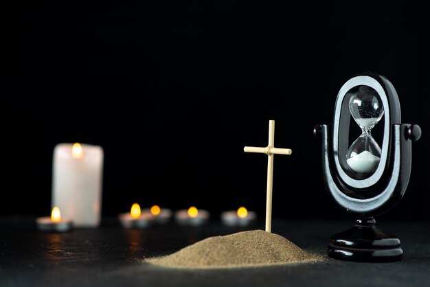 Front view of little grave with hourglass and candles dark