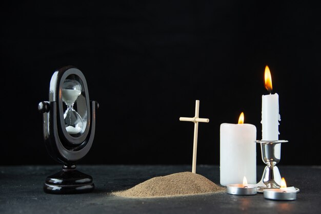 Front view of little grave with hourglass and candles on dark