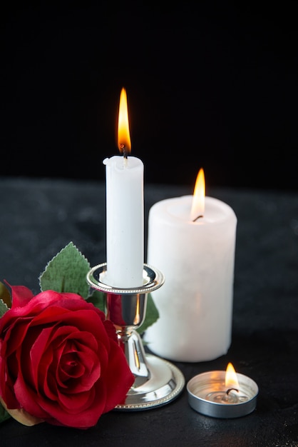 Front view of little grave with red rose and candle on black