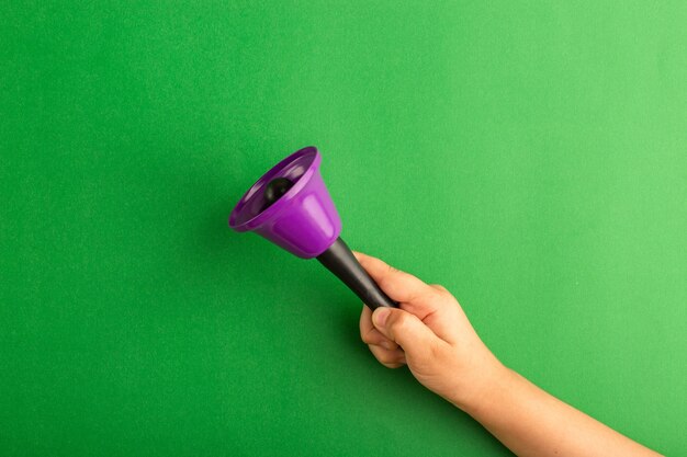 Front view little kid holding purple bell on green surface