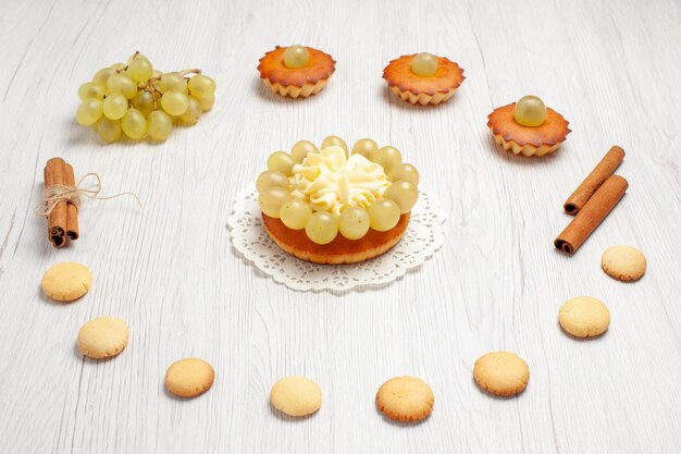 Front view little yummy cakes with grapes and cookies on white desk cake biscuit sweet dessert cookie