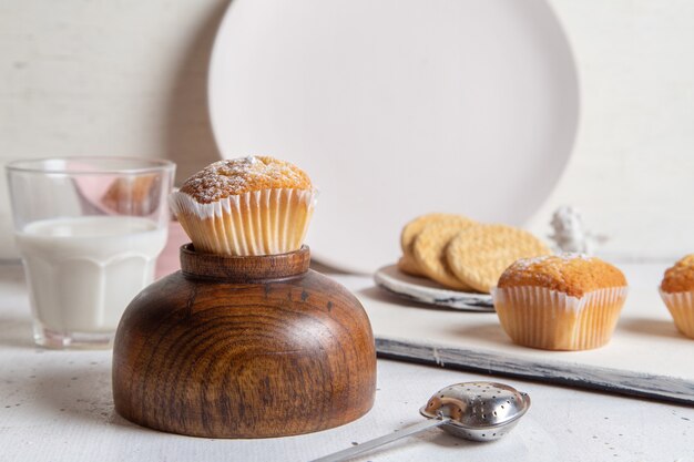 Front view of little yummy cakes with sugar powder milk and cookies on the white surface