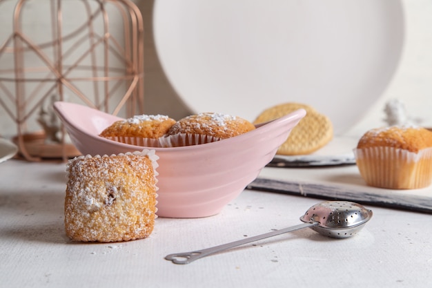 Front view of little yummy cakes with sugar powder on the white surface