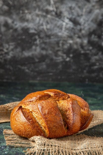 Front view of a loaf of dietary black bread on brown towel on dark colors surface with free space