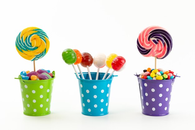 A front view lollipops and candies inside little baskets on white, sugar sweet confiture color