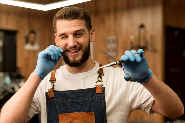 Front view of male barber holding scissors in the barbershop