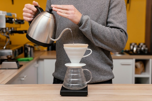 Free photo front view of male barista pouring hot water over coffee filter