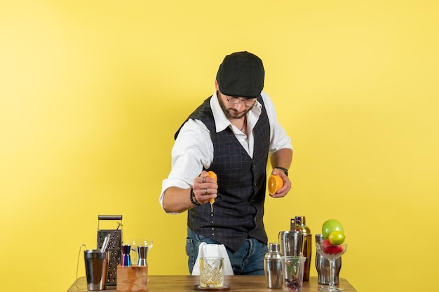 Front view male bartender in front of bar desk making drink on light yellow wall bar alcohol night youth drink club