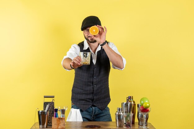 Front view male bartender in front of bar desk making drink on a yellow wall bar alcohol night youth drink club