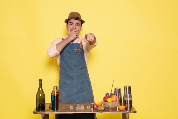 Free photo front view male bartender in front of table with drinks and shakers laughing on yellow wall night alcohol male drink club bar