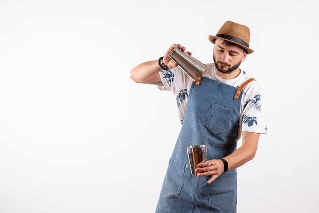 Front view male bartender holding shaker and making a drink on white wall club night bar alcohol drink job color