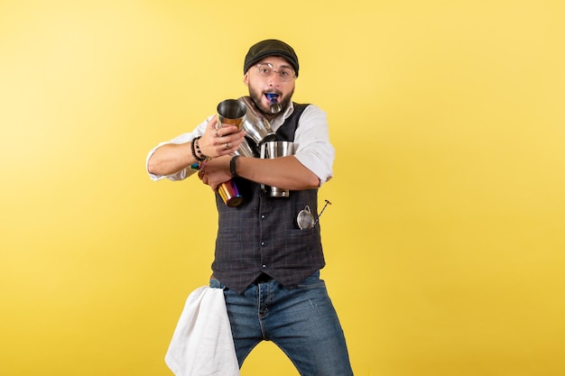 Front view male bartender holding shakers on the yellow wall drink alcohol job night male club bar