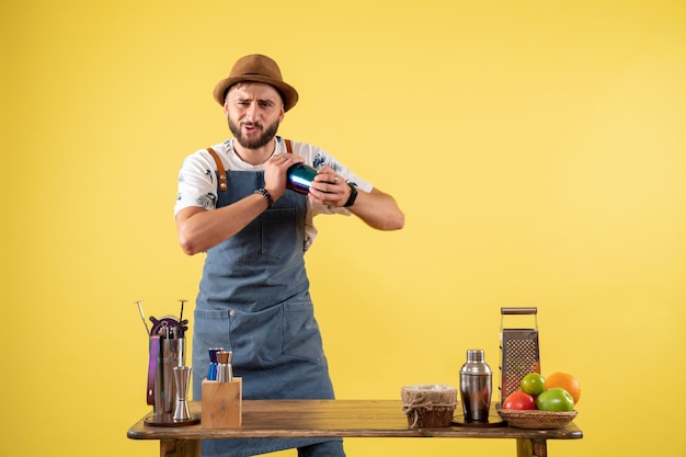 Free photo front view male bartender preparing a drink on a yellow wall club night bar alcohol drink job color