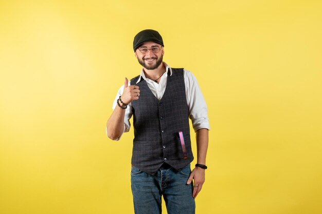 Front view male bartender standing and smiling on yellow wall drink alcohol night male club bar job