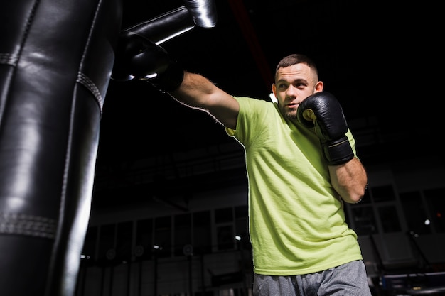 Front view of male boxer practicing with punching bag