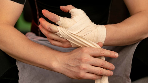 Free photo front view of male boxer putting on protection for hands before exercising