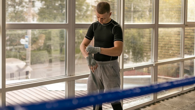 Free photo front view of male boxer wrapping his hands before training in the ring