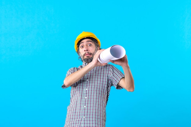 Front view male builder holding plan on blue background building job architecture skyscraper constructor engineers