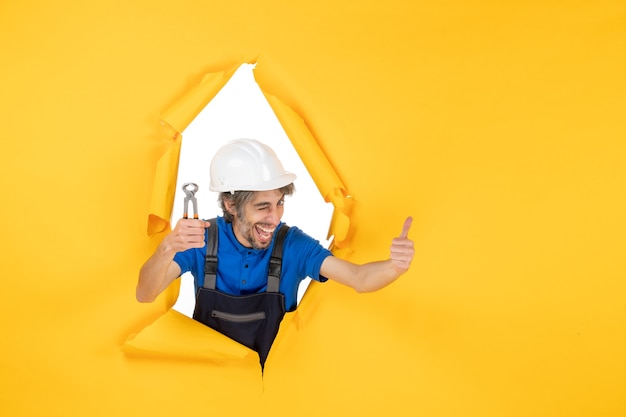 Free Photo front view male builder holding pliers on yellow background