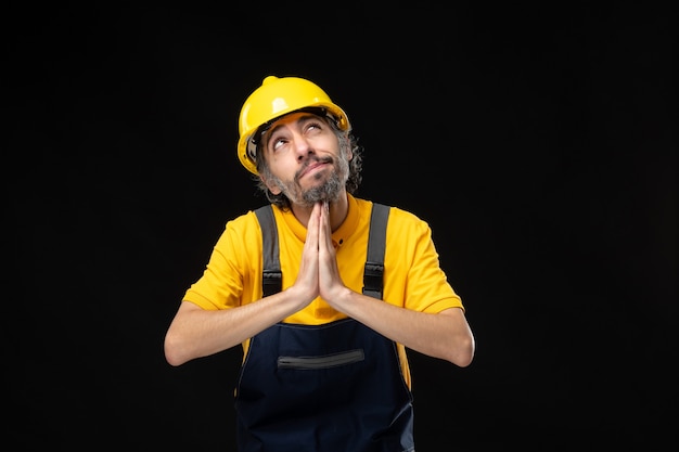 Front view of male builder in uniform on black wall