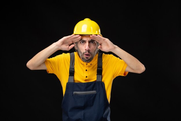 Front view male builder in uniform on black wall