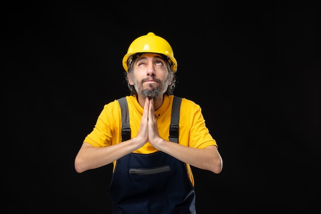 Front view male builder in uniform on black wall