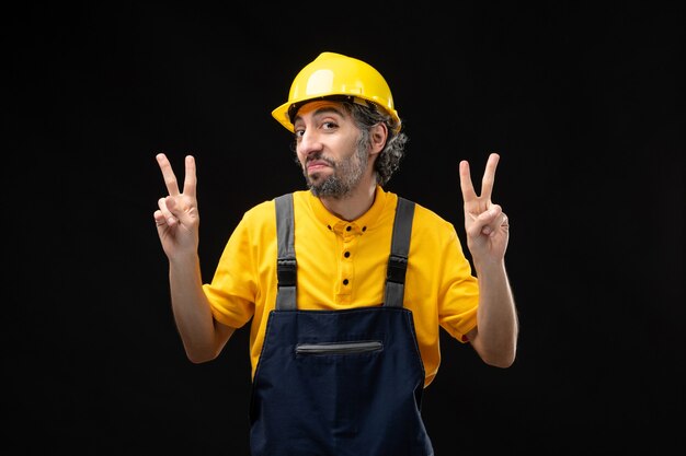 Front view of male builder in uniform on black wall