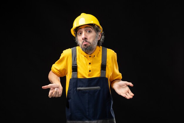 Front view of male builder in uniform on black wall