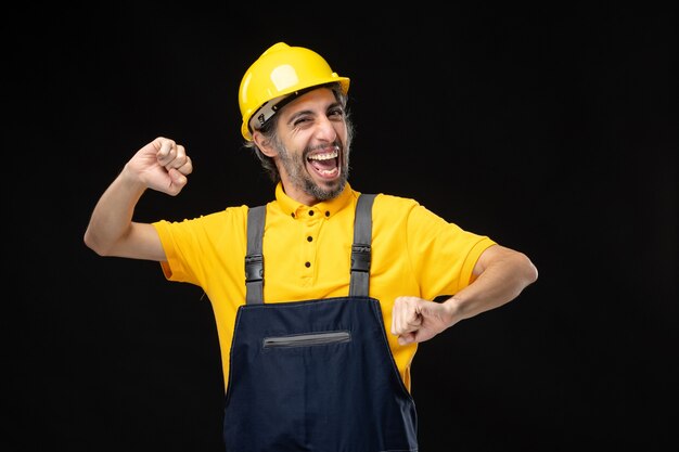 Front view male builder in uniform on the black wall