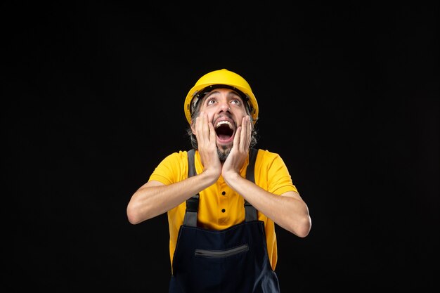 Front view of male builder in uniform on the black wall