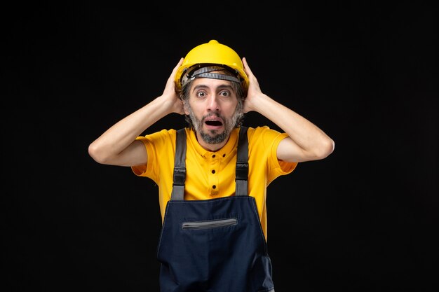 Front view male builder in uniform on black wall